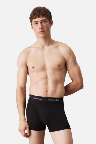 Zwarte boxershort van Calvin Klein, gedragen door een model met ontbloot bovenlichaam en de handen achter de rug.
