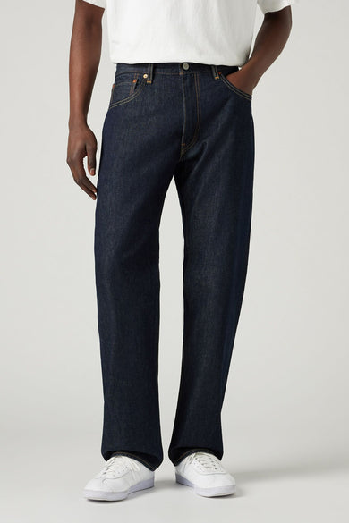 Donkerblauwe straight jeans van Levi's, met gele stiksels en gedragen met een wit T-shirt en witte sneakers.
