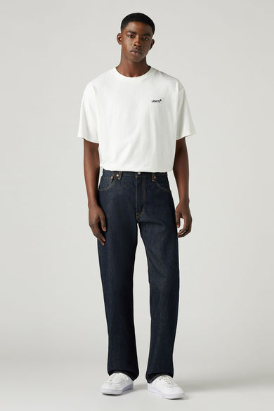 Donkerblauwe straight jeans van Levi's, gedragen met een wit T-shirt en witte sneakers.
