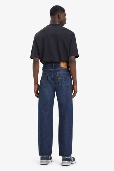 Jean bleu droit de Levi's, vu de derrière, combiné avec un T-shirt noir et des baskets bleues.
