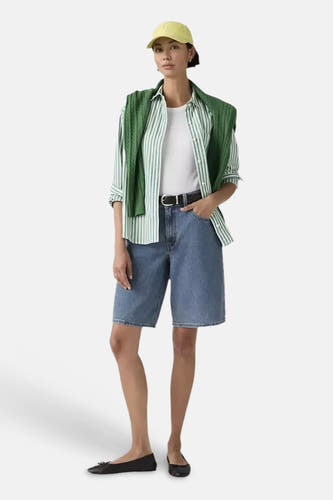 Blauwe denim shorts met middelhoge taille van Levi's, gedragen met gestreept overhemd, groene vest en gele pet, volledige vooraanzicht.