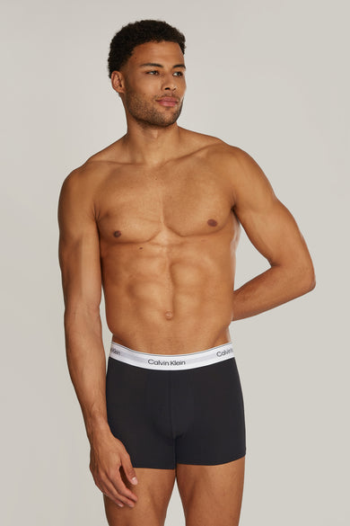 Zwarte boxershort van Calvin Klein, gedragen door een gespierde man met zijn hand op zijn rug.
