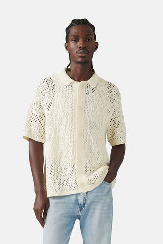 T-shirt blanc tricoté à manches courtes de Levi's, avec un motif ajouré ouvert, porté avec des jeans bleu clair.