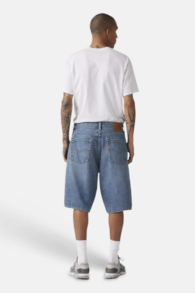 Lichtblauwe denim short van Levi's®, achterkant, met zakken en leren patch, gedragen door een man met een wit T-shirt.