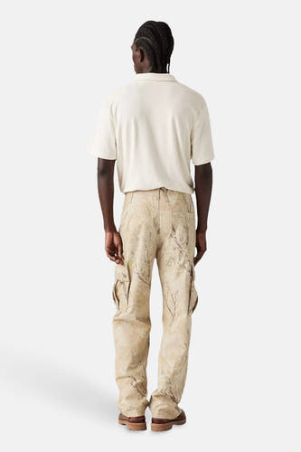 Pantalon cargo beige de Levi's® avec imprimé camouflage, porté avec un polo crème et des chaussures brunes, vue arrière.