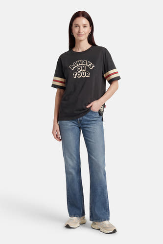 Zwart T-shirt met korte mouwen van Levi's®, met opschrift "Always on tour" en strepen op de mouwen, gecombineerd met jeans en sneakers.
