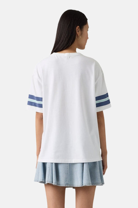 Wit T-shirt van Levi's® met blauw-groene strepen op de mouwen, gedragen met een denim rok.
