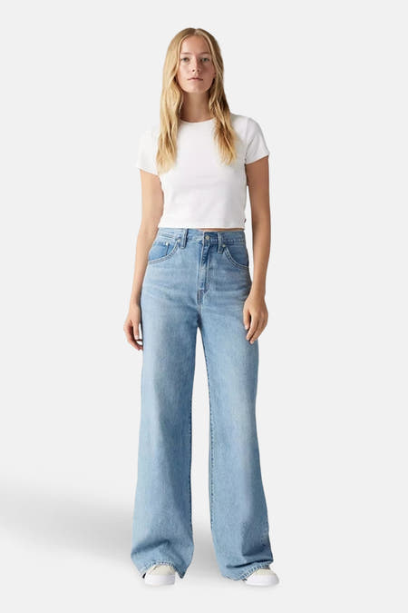 Jean décontracté de denim bleu clair de Levi's®, porté avec un T-shirt blanc et des baskets blanches.
