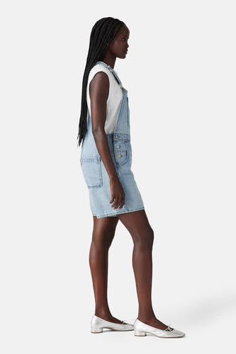 Denim playsuit in lichtblauw denim van Levi's®, met een witte top en zilverkleurige schoenen.