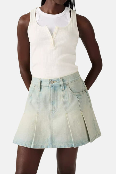 Korte rok van lichtblauwe denim van Levi's, met plooien en een knoopsluiting, gecombineerd met een wit hemdje.
