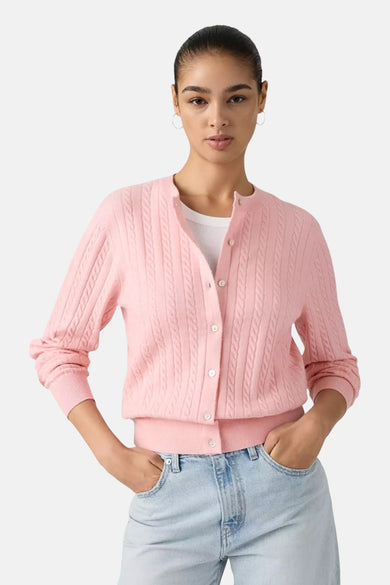 Roze vest van Levi's® met kabelpatroon, geknoopt en gedragen over een wit T-shirt en een blauwe jeans.