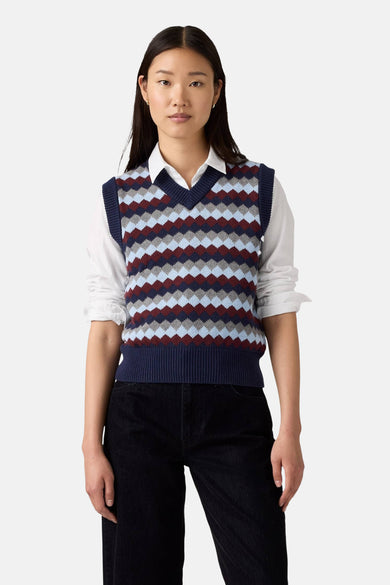 Multikleurige debardeur van Levi's met een ruitpatroon, gedragen over een wit overhemd en zwarte jeans.
