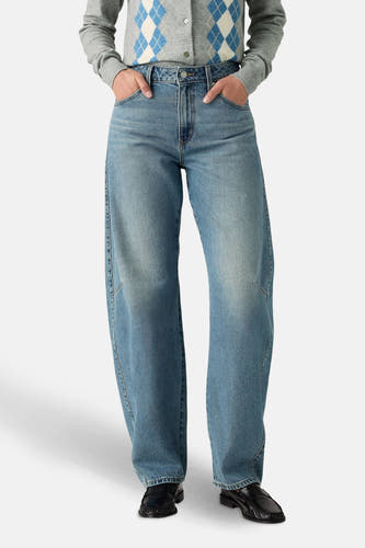 Jean en denim bleu clair de Levi's, avec une coupe décontractée et porté avec un cardigan gris à carreaux.