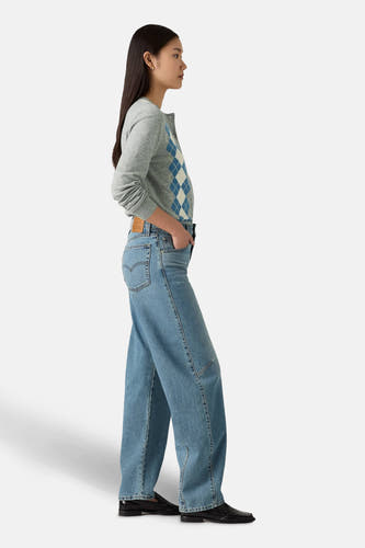 Lichtblauwe denim jeans van Levi's, met losse pasvorm en gedragen met een grijze cardigan met ruitpatroon.
