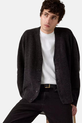 Grijs vest van Levi's, gedragen over een wit shirt met zwarte jeans en riem met gouden gesp.
