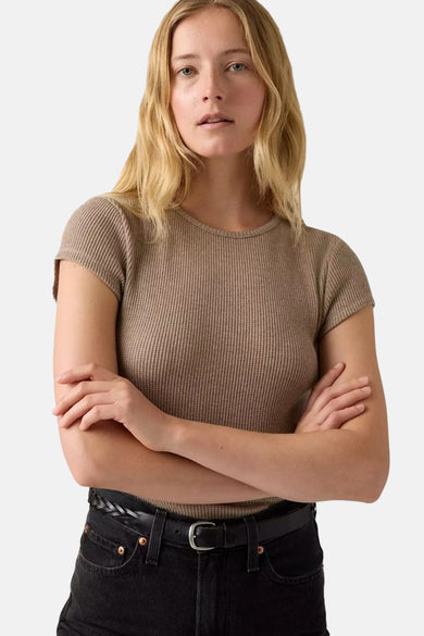 T-shirt beige à manches courtes de Levi's, avec une subtile texture côtelée et associé à un pantalon noir et un ceinture.