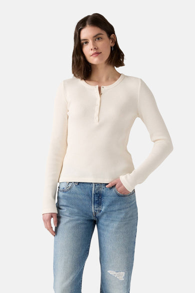 T-shirt blanc à manches longues de Levi's, avec fermeture à boutons et porté avec des jeans bleus.