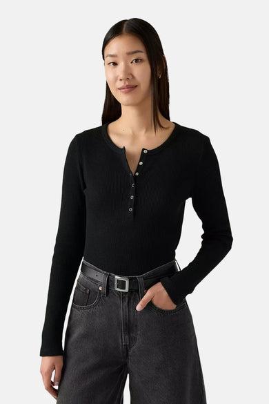 T-shirt noir à manches longues de Levi's, avec des boutons au col et associé à un pantalon noir avec cece.