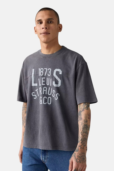 Grijs T-shirt met korte mouwen van Levi's®, met witte print en gedragen met een blauwe jeans.
