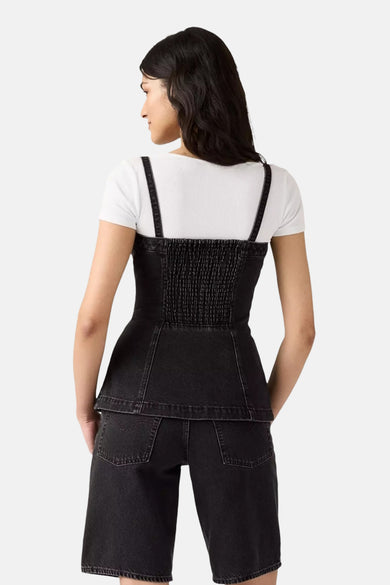 Zwarte denim tuniek van Levi's®, gedragen over een wit shirt, met schouderbandjes en korte broek.