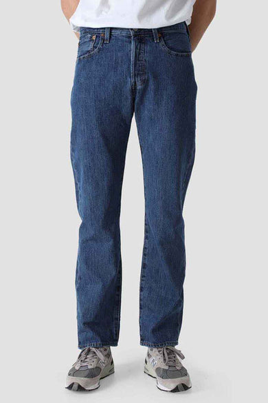 Blauwe straight jeans van Levi's, met een denim textuur en gedragen met grijze sneakers.
