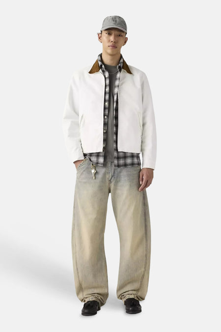 Wijde jeans van Levi's® in lichtblauwe faded denim met speciale pasvorm, gedragen met wit jack en geruit overhemd.