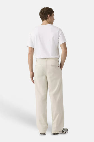 Beige chino met wijde pijpen van Levi's®, met paspelzakken, gedragen door een man met wit T-shirt en sneakers.