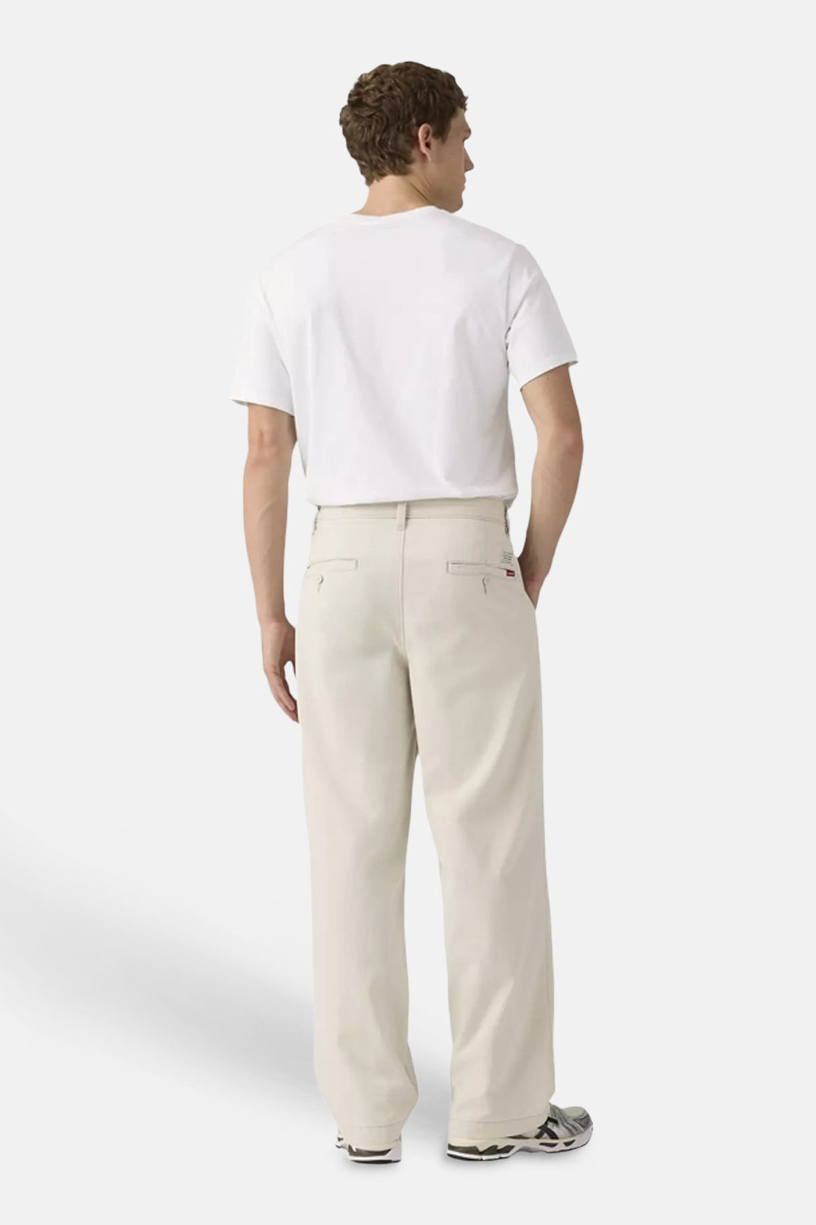 Beige chino met wijde pijpen van Levi's®, met paspelzakken, gedragen door een man met wit T-shirt en sneakers.