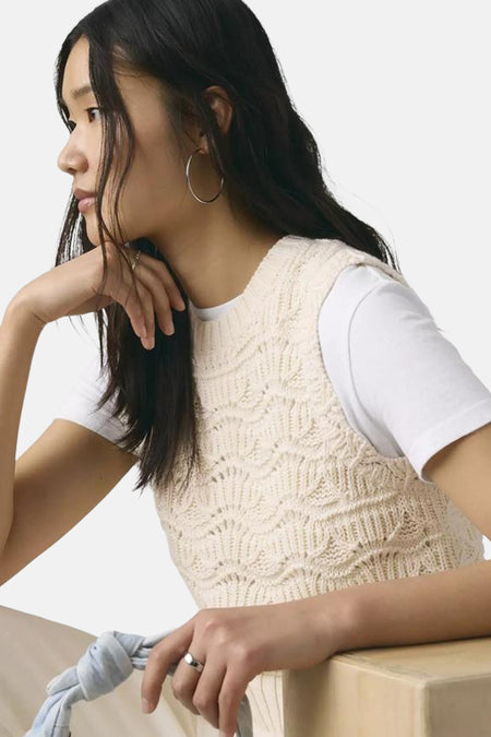 Witte mouwloze top van Levi's® met een gebreid golvend patroon, gedragen over een wit T-shirt.