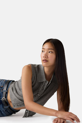 Mouwloze grijze top van Levi's, met knoopsluiting en gedragen met een blauwe jeans en zwarte riem.
