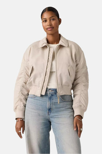 Grijze korte jas van Levi's, met rits en zakken, gedragen met een witte top en lichtblauwe jeans.
