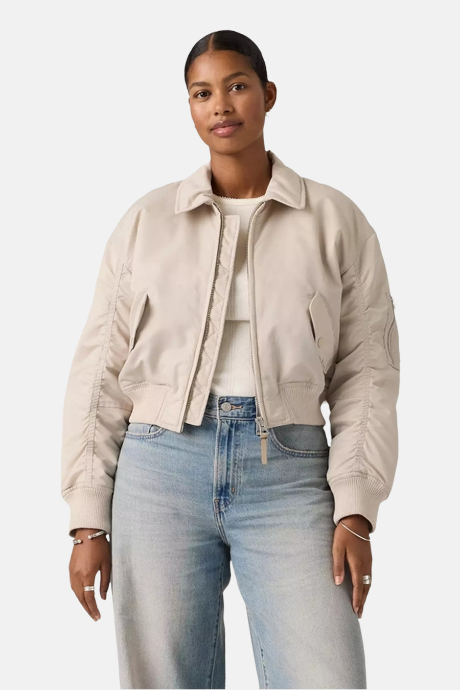 Grijze korte jas van Levi's, met rits en zakken, gedragen met een witte top en lichtblauwe jeans.
