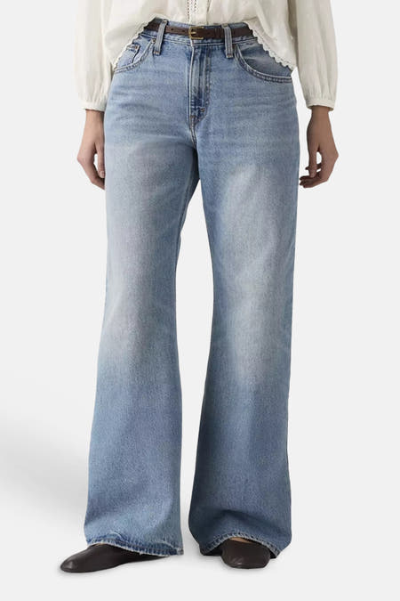 Lichtblauwe denim bootcut jeans van Levi's®, met hoge taille en wijde pijpen, gedragen met een witte blouse en donkerbruine riem.