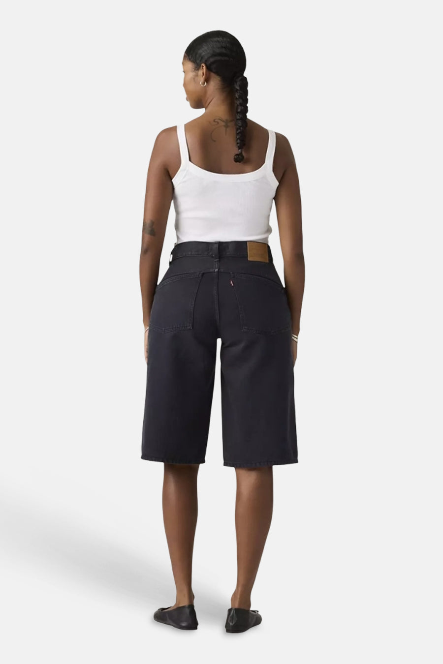Zwarte short van Levi's® met leren patch en rode tab op de achterzak, achterzicht van model in witte tanktop.