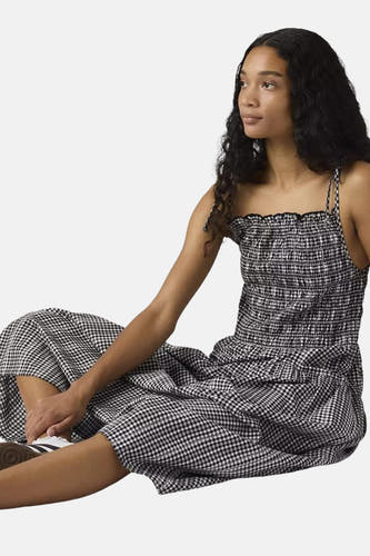 Zwart-wit geruite lange jurk van Levi's® met gesmokt lijfje en dunne bandjes, gedragen door zittend model.