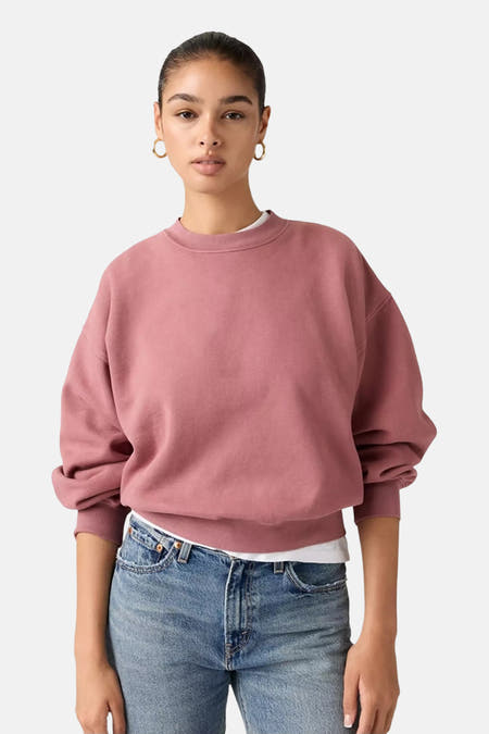 Pull-over rose avec col rond de Levi's®, porté avec des boucles d'oreilles en or et un t-shirt blanc en dessous.