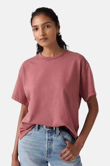 Roze T-shirt met korte mouwen van Levi's, gedragen met een blauwe jeans met een zwarte riem.
