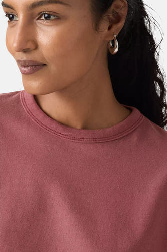 T-shirt Levi's à manches courtes rose, gros plan avec une femme portant des boucles d'oreilles en argent.