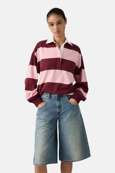 Multikleurige sweater van Levi's, met roze en bordeauxrode strepen, lange mouwen en een witte kraag, gecombineerd met een wijde denim broek.
