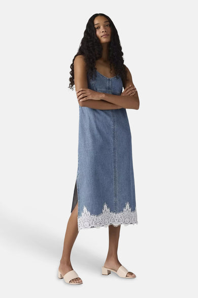 Blauwe mouwloze denim jurk van Levi's met witte kantzoom, model in front view met beige slippers