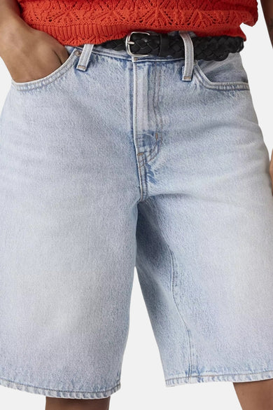 Lichtblauwe denim short van Levi's® met een gevlochten zwarte riem, zilveren gesp en een hand in de zak.