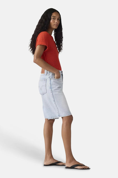 Lichtblauwe denim short van Levi's® met knielengte, in zijaanzicht en met handen in de zakken.