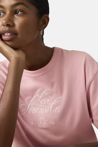Roze korte mouw T-shirt van Levi's® met witte borduurwerk logo en vintage tekst, gedragen door model in close-up zijaanzicht
