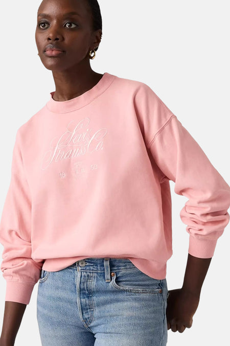 Gile rose de Levi's, avec des manches longues et un col rond, associé à des jeans bleus.