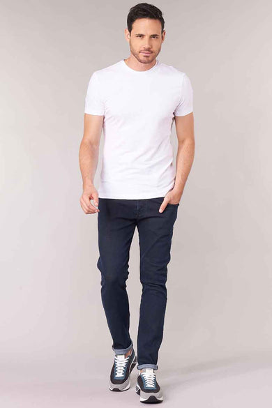 Donkerblauwe tapered jeans van denim van Diesel, met opgerolde pijpen, gedragen met wit T-shirt en sneakers, front view.