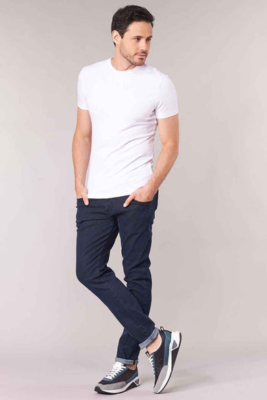 Donkerblauwe tapered jeans van denim van Diesel, gedragen met wit T-shirt en sneakers, volledige lengte lifestyle shot