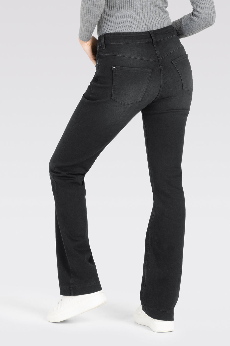 Donkergrijze bootcut jeans van MAC, met achterzakken, gecombineerd met een grijze top en witte sneakers.

