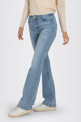 Bootcut jeans van lichtblauw denim van MAC, gedragen met een gebreide trui en witte sneakers.