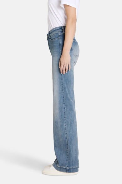 Wijde jeans van lichtblauw denim van MAC, met een effen wassing en witte sneakers.
