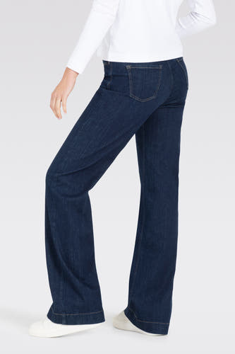Jean bleu marine large de MAC, avec des poches arrière et associé à un t-shirt blanc et des chaussures blanches.